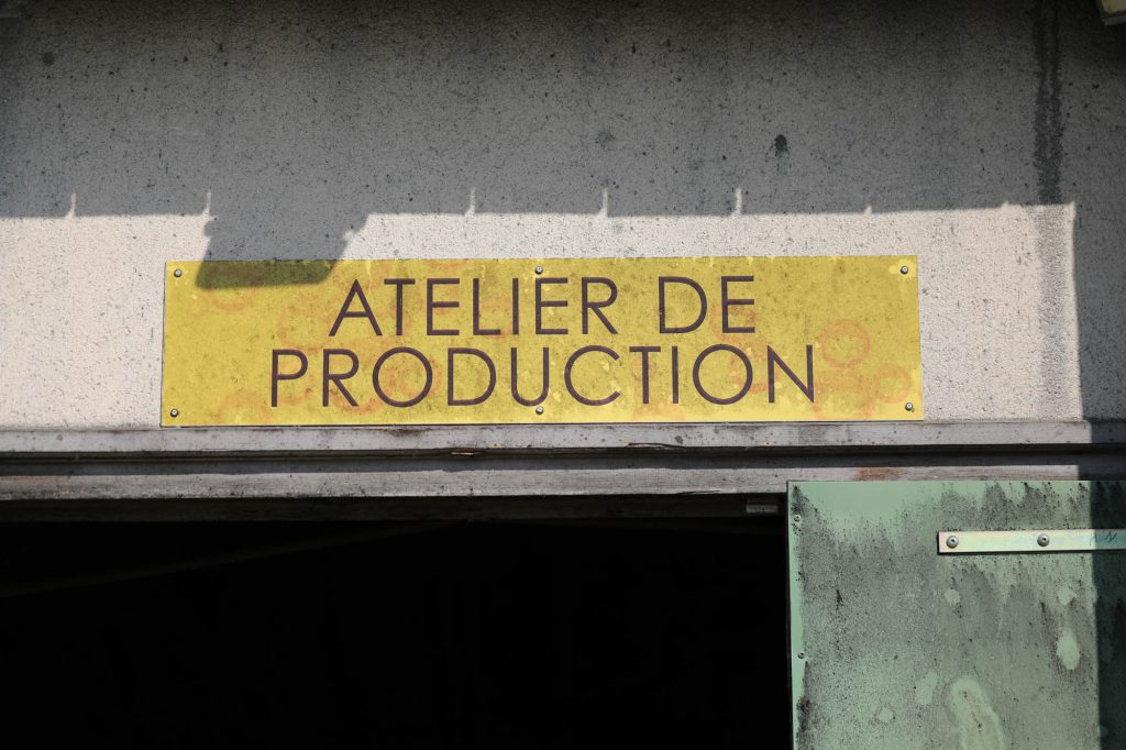 Enseigne jaune « Atelier de Production » au-dessus de la porte d'entrée