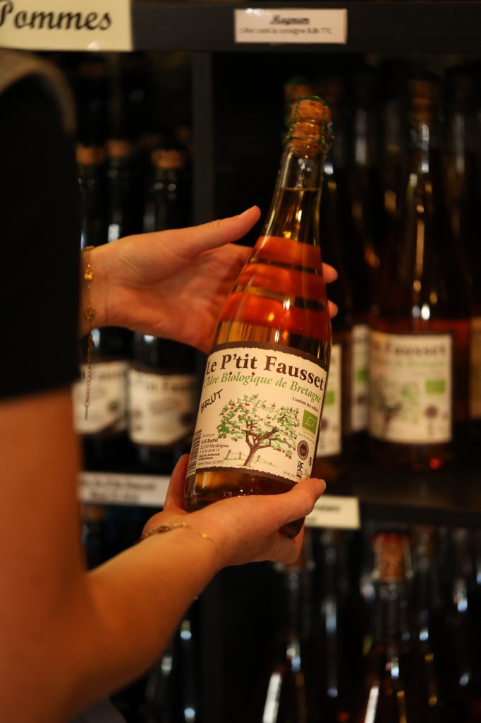 Main tenant une bouteille de cidre biologique brut Le P'tit Fausset bouchon liège